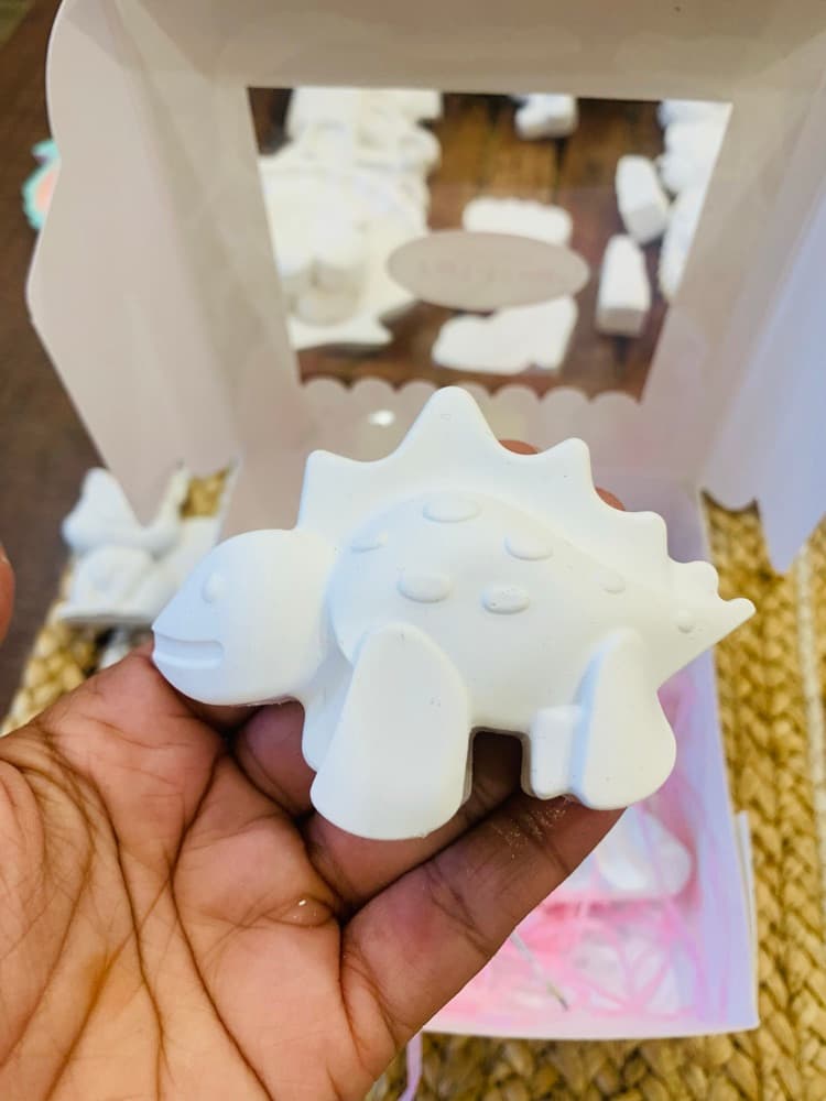Unpainted white stegosaurus figurine held in hand