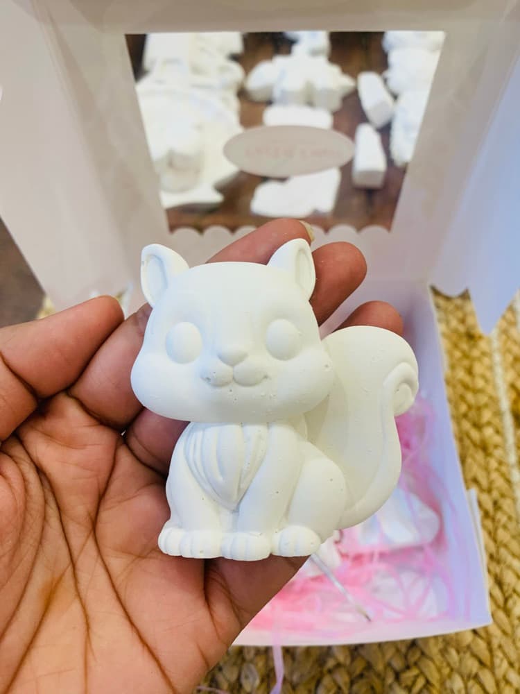 Unpainted white squirrel figurine held in hand